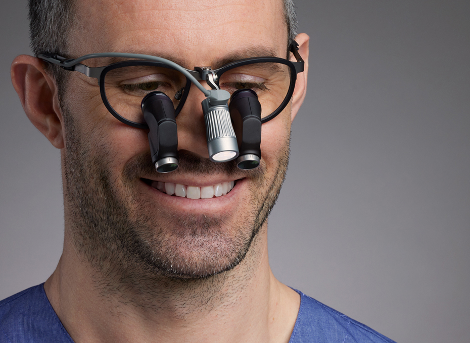Male dentist wearing ergo loupe Kepler Reflekt together with Total LED loupe light 